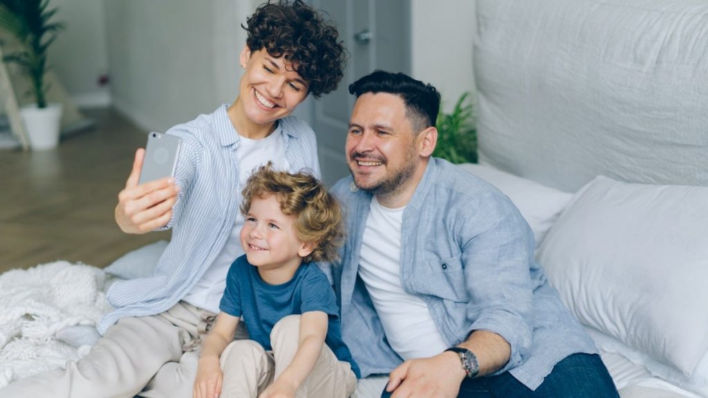 Perfect family girl guy and kid taking selfie at home in bed using smartphone